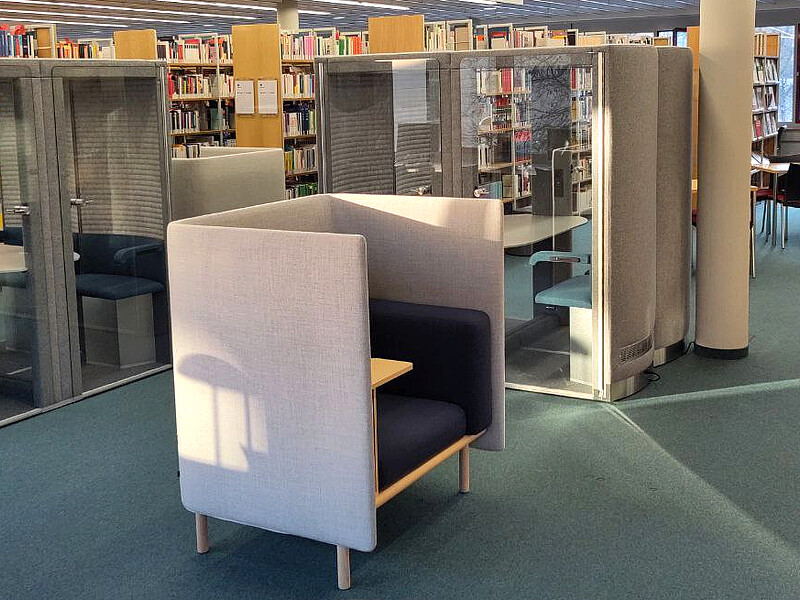 Blick in den Leseraum, Sessel im Vordergrund, Flüsterboxen und Regale im Hintergrund